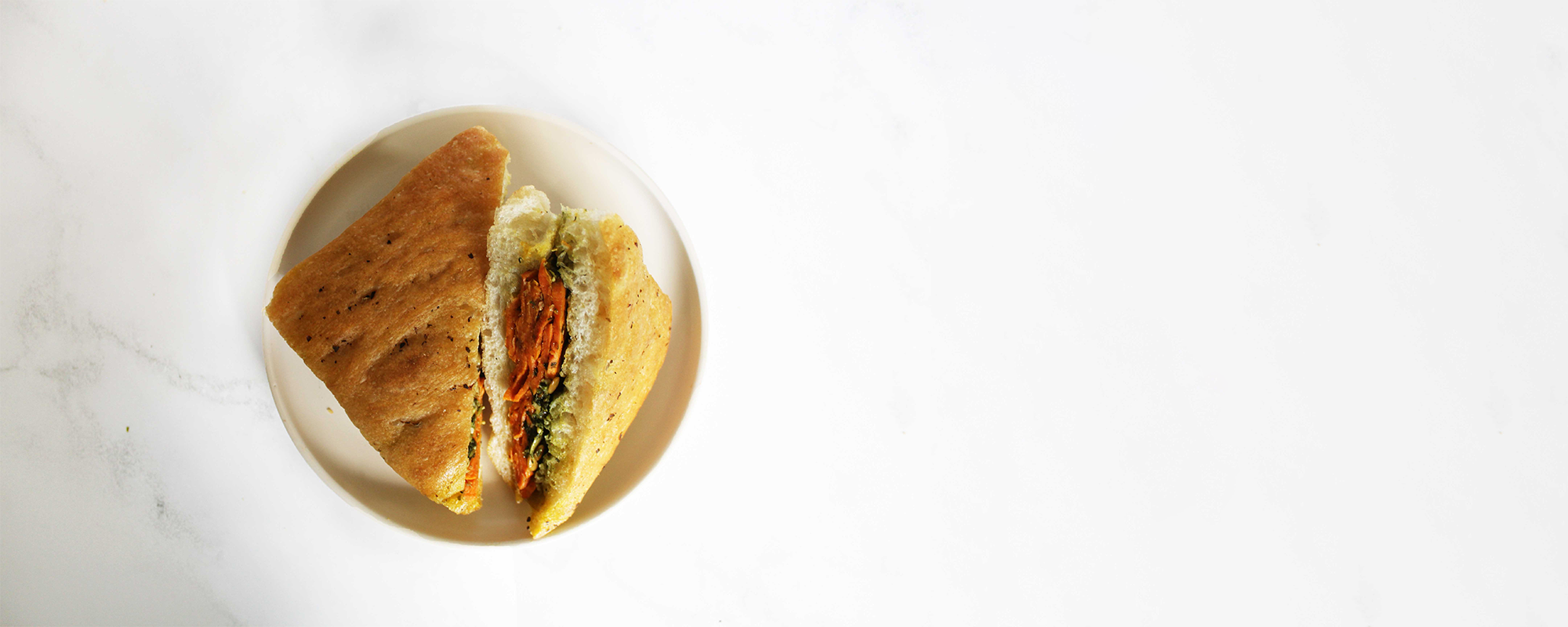 vegetarian panino sandwich with sweet potato and basil pesto. Served with pumpkin seeds on focaccia bread.